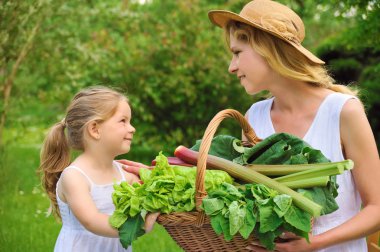 Young woman and daughter with fresh vegetable clipart