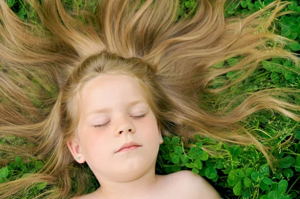 Pequena menina tomando banho de sol - deitado na grama — Fotografia de Stock