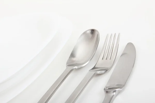 Tenedor, cuchara y cuchillo con platos blancos — Foto de Stock