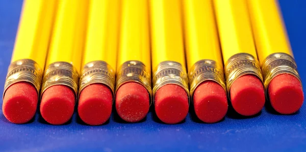 行的黄色铅笔与红色橡胶的蓝色背景 — 图库照片