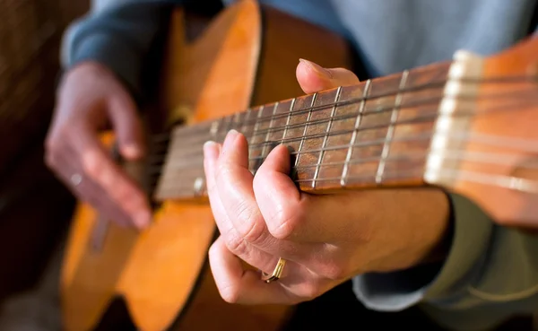 Guitare brune entre les mains du gars qui la joue — Photo