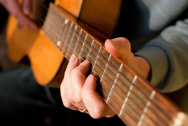 Guitare brune entre les mains du gars qui la joue — Photo