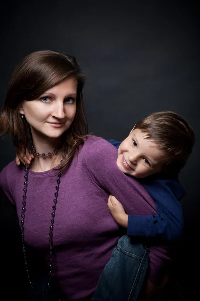 Мать держит его сына на спине — стоковое фото
