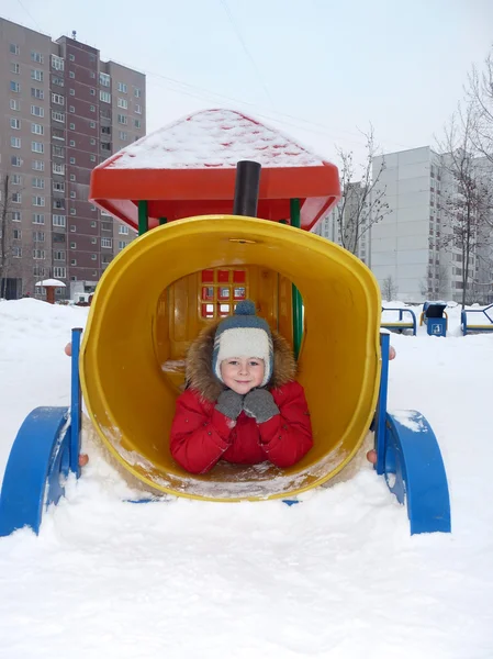 Мальчик играет на детской площадке зимой — стоковое фото