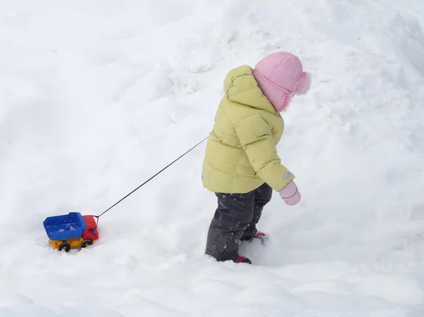 子は雪の中でおもちゃの車を運ぶ — ストック写真