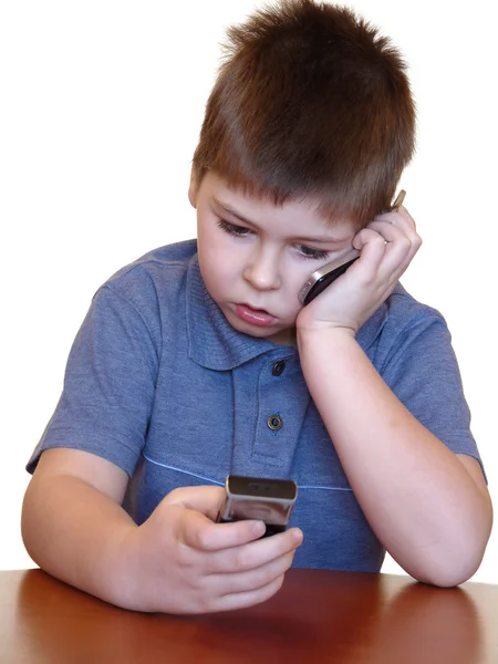 Der Junge mit zwei isolierten Mobiltelefonen auf weißem Hintergrund — Stockfoto