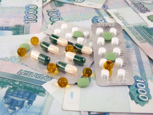 Tablets against the backdrop of the money. Treatment costs — Stock Photo, Image