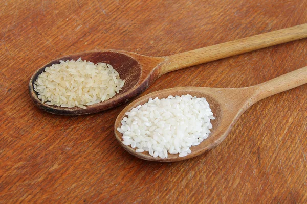 Ahşap zemin üzerinde pişmemiş beyaz pirinç. — Stok fotoğraf