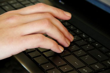 Close up of woman's hand on computer keyboards clipart