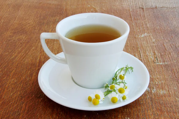 Chá de ervas com camomila em uma mesa de madeira — Fotografia de Stock