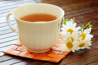 Herbal tea with camomile on a wooden table clipart