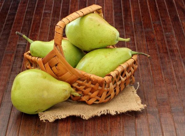 Ripe pears in a basket on a wooden background — Stock Photo, Image