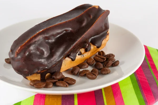 Eclair and cofee beans — Stock Photo, Image