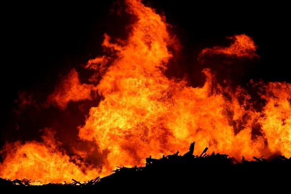 巨大な火は明るいオレンジ色の炎とシルエットの木材 — ストック写真
