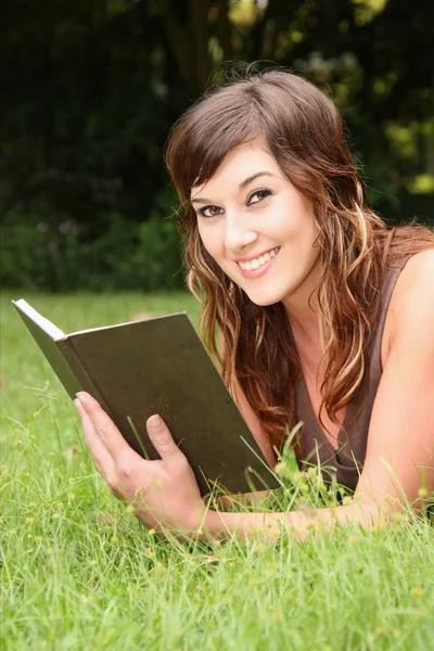 屋外の本を読んで美しい若いブルネットの女性 — ストック写真