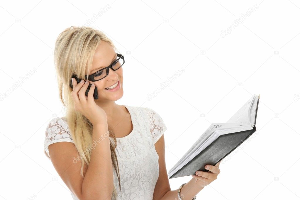 Beautiful young blond woman talking on mobile phone and checking her diary
