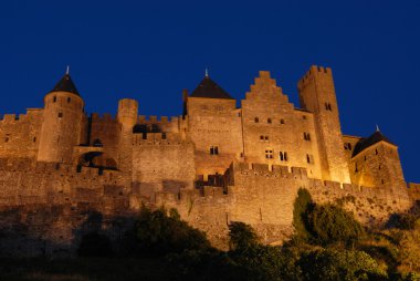 The illuminated walls and towers of the medieval city of Carcassonne, France. clipart