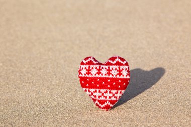 Red knitted heart on sea sand clipart