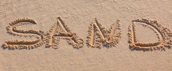 単語「砂」ビーチに書かれて — ストック写真