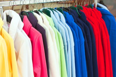 Colourful Textile sport shirts hanging in row at store clipart