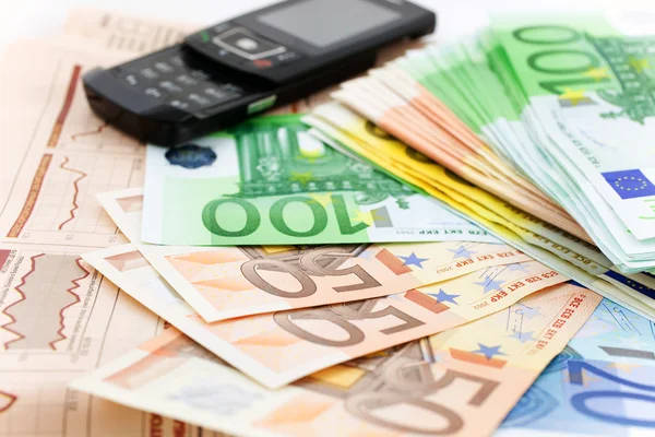Billets Euro et téléphone portable noir sur un journal financier — Photo