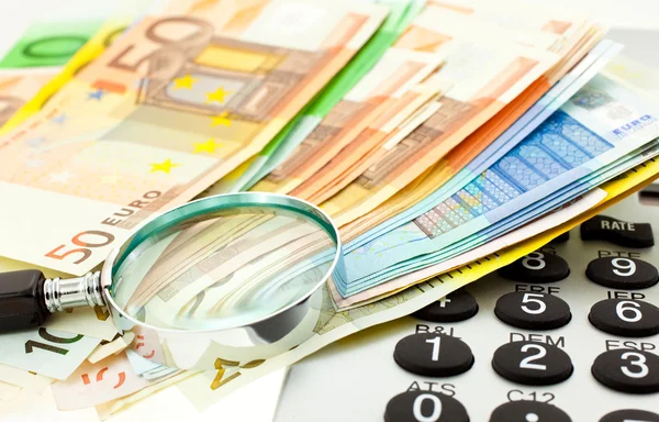 Банкноты евро с калькулятором и лупой — стоковое фото