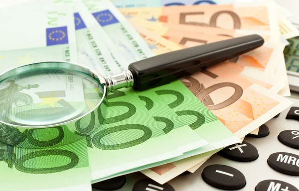 Billetes en euros con calculadora y lupa — Foto de Stock