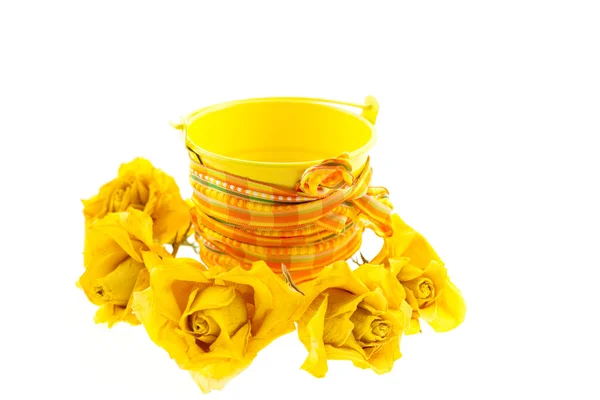 Suché žluté růže a kýbl s oranžovou mašlí — Stock fotografie