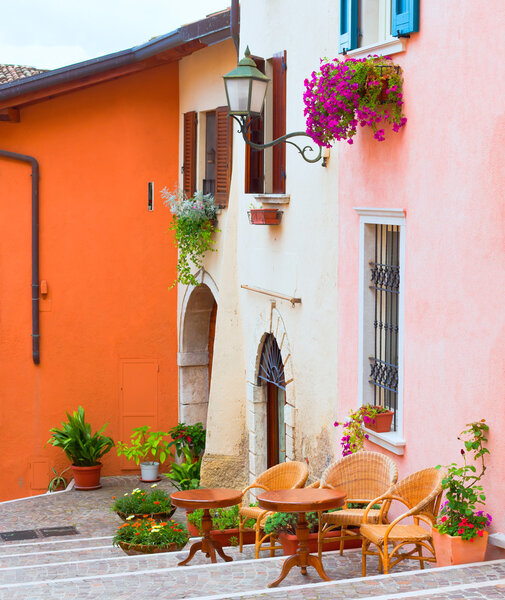 Traditional italian small town street with pots of flowers and cafe