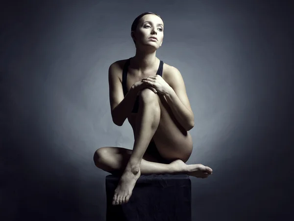 黒の背景に裸の美しい座っている女性 — ストック写真