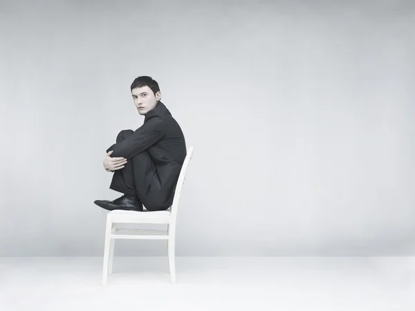 Человек сидит на белом стуле — стоковое фото