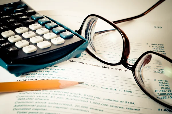 Eye glasses on an accounting book with pencil and calculator