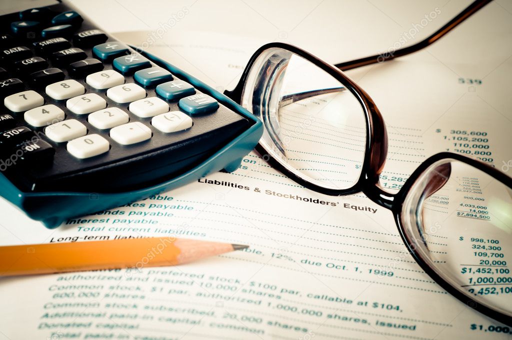 Eye glasses on an accounting book with yellow pencil and calculator with vintage feel