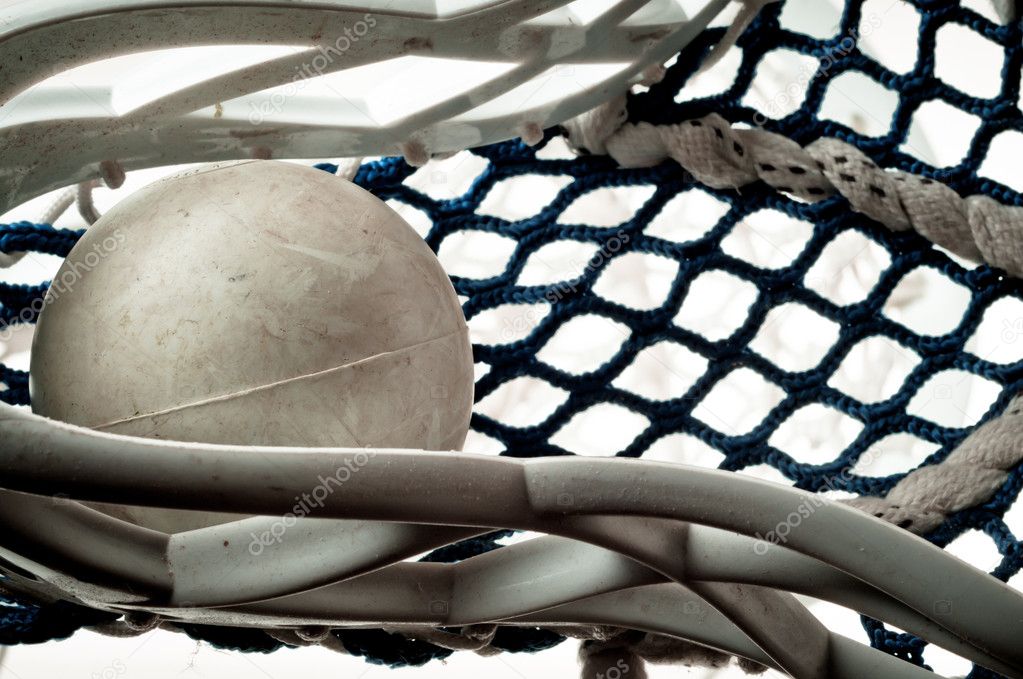 Gray lacrosse ball held in the head with blue netting