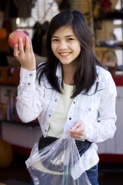 Young girl picking out apples at a farmer's market clipart