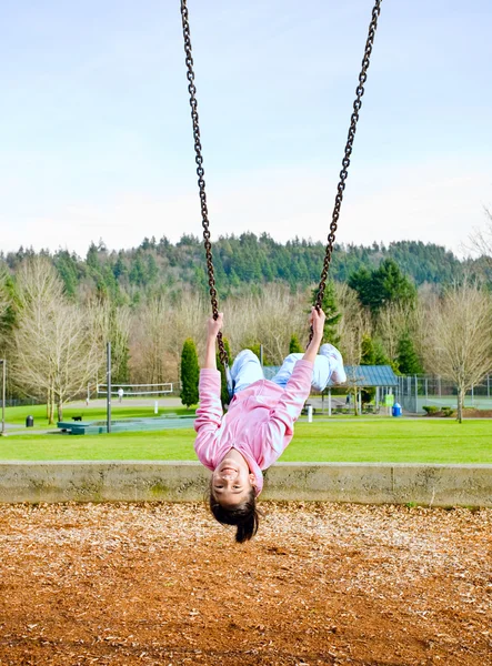 Happy little nine year old part Asian girl on the swings at park — Stock Photo, Image
