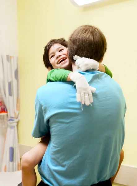 Liten pojke sitter i läkarmottagningen, skrattar — Stockfoto