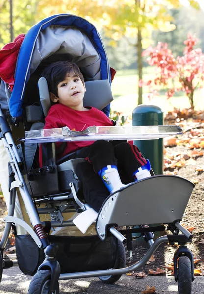Menino com deficiência no carrinho médico ao ar livre — Fotografia de Stock