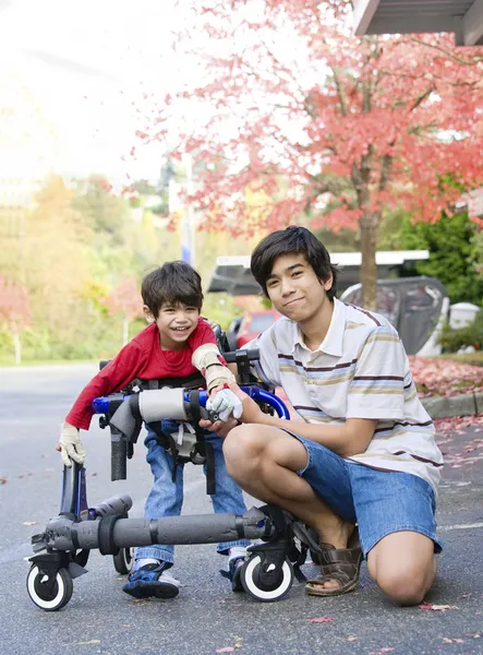 Adolescente menino com deficiente irmãozinho — Fotografia de Stock