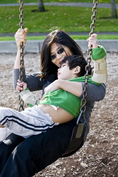 Mãe balançando com seu filho deficiente — Fotografia de Stock