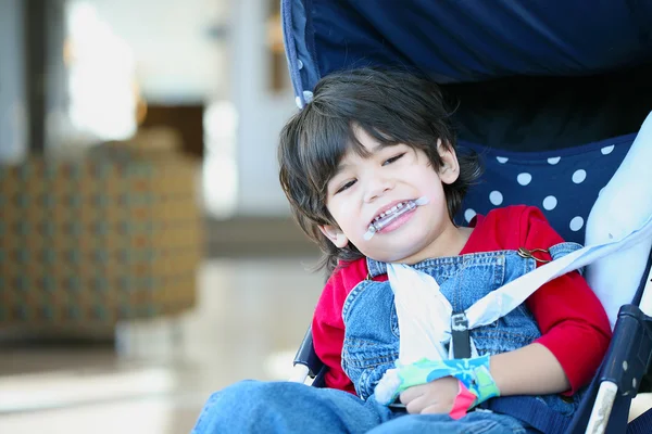 Ładny chłopak niepełnosprawnych z mózgowym porażeniem dziecięcym uśmiechający się w wózek — Zdjęcie stockowe