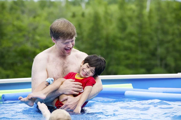 Отец держит сына-инвалида в бассейне — стоковое фото