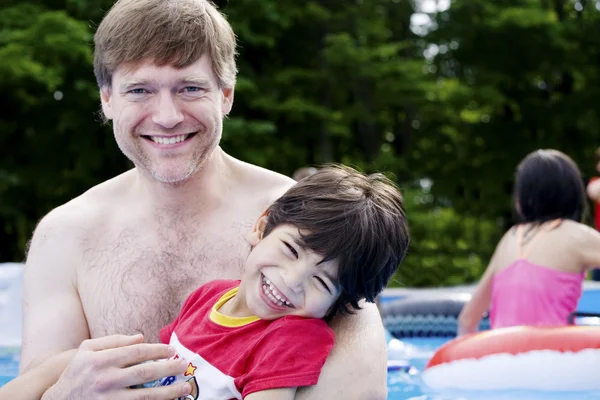 Pai segurando filho deficiente na piscina — Fotografia de Stock