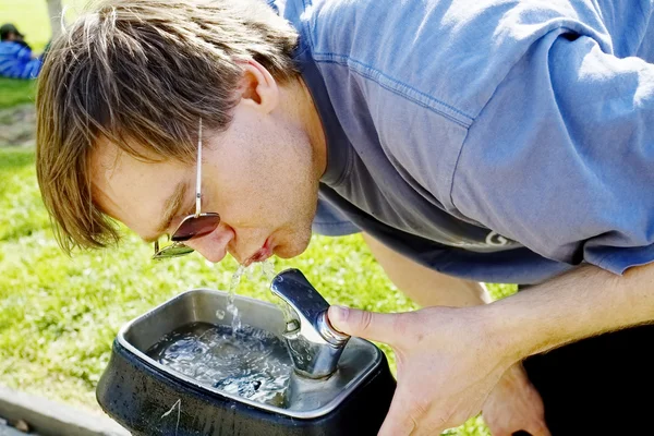 Человек пьет воду из фонтана — стоковое фото
