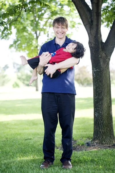 Pai segurando filho deficiente ao ar livre — Fotografia de Stock