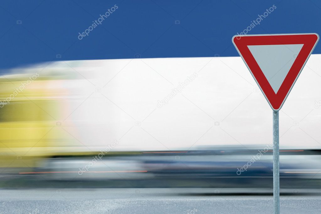Give way yield road traffic sign and motion blurred truck in the background
