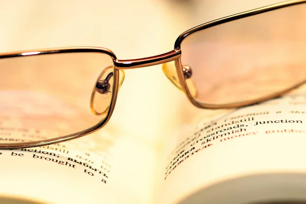 Lendo óculos em um livro em sépia — Fotografia de Stock