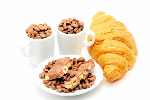 Duas xícaras e prato cheio de grãos de café e croissant — Fotografia de Stock