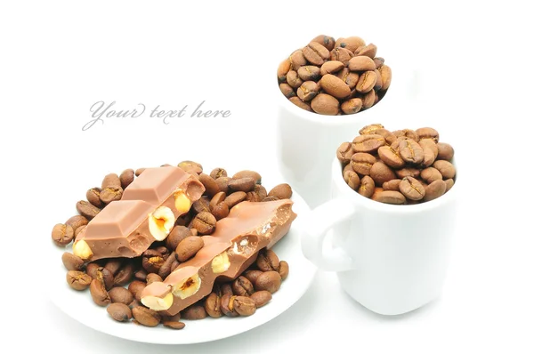 Två koppar och tallrik fylld med kaffebönor och choklad — Stockfoto
