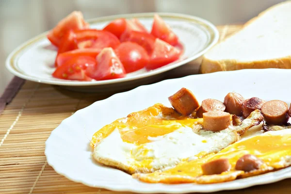Завтрак с яйцами, колбасой, хлебом и помидорами — стоковое фото